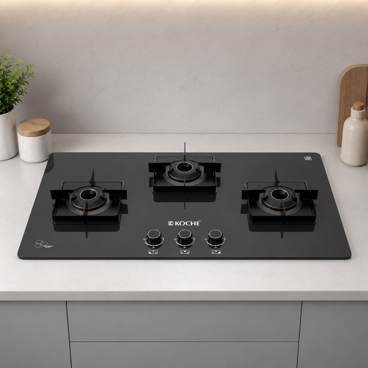 Köche Betty 3 burner gas hob with black toughened glass, premium brass burners, and three metal pan supports, front view.