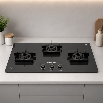 Köche Betty 3 burner gas hob with black toughened glass, premium brass burners, and three metal pan supports, front view.