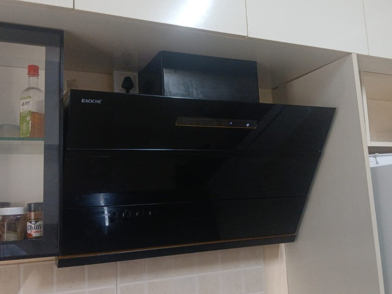   Laura 90cm Ducted BLDC Chimney | 1650 CMH Suction | Auto Clean A black glossy KOCHE Laura range hood installed under white kitchen cabinets. 